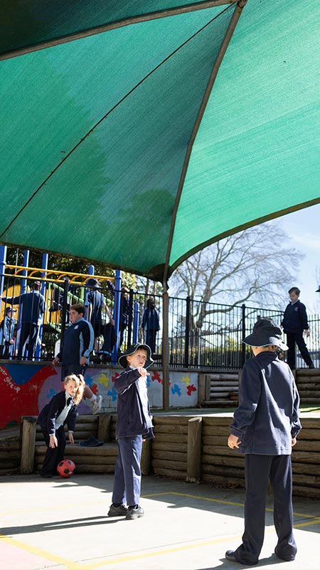 Before and after school care at Our Lady of the Nativity, Lawson. The students are playing soccer, and the playground equipment (Slides, monkey bars) is in the background.