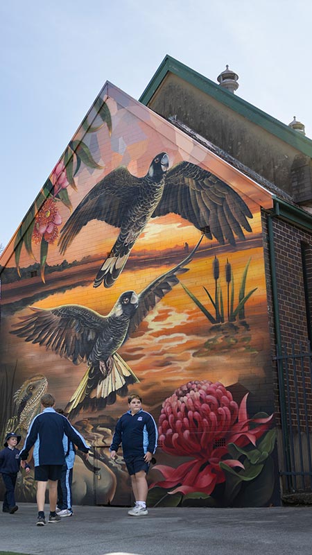 Outside view of the Church at Our Lady of the Nativity Primary Lawson. There is a mural of birds flying over Australian native bush