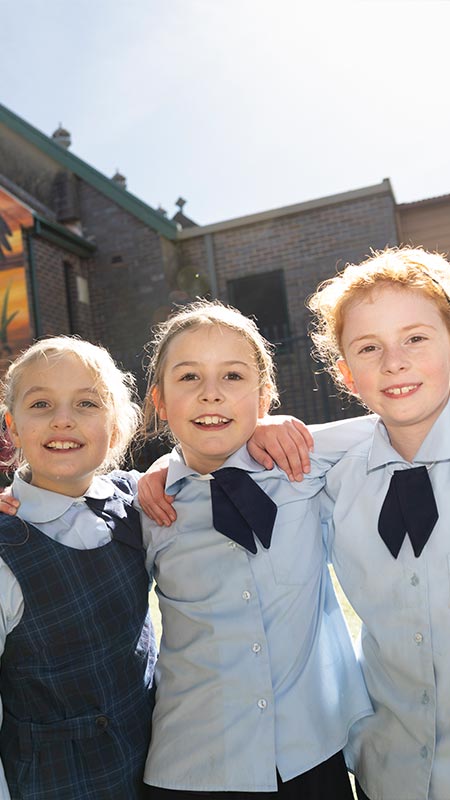 Three OLN Lawson students outdoors. They are smiling and have their arms wrapped around each other.