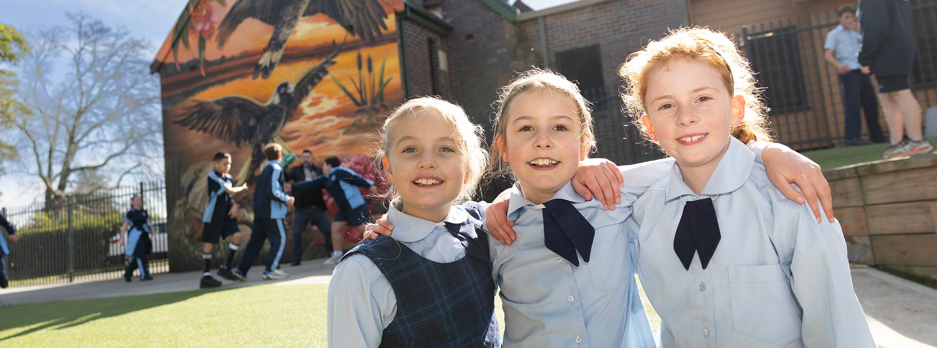 Three OLN Lawson students outdoors. They are smiling and have their arms wrapped around each other.