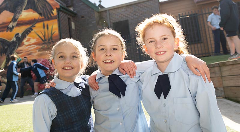 Three OLN Lawson students outdoors. They are smiling and have their arms wrapped around each other.