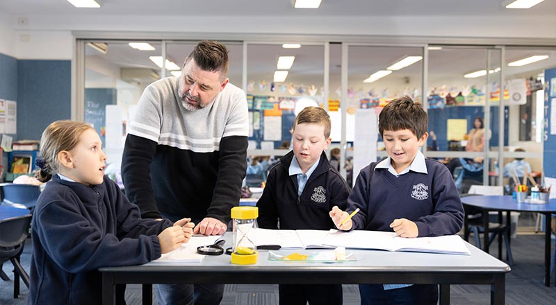 Our Lady of the Nativity Primary Lawson students in class. A teacher is assisting them.