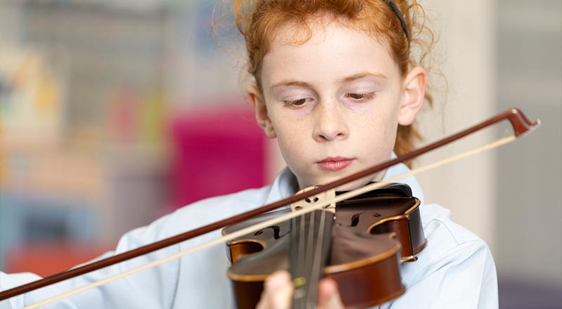 Our Lady of the Nativity Primary Lawson student playing string instrument.