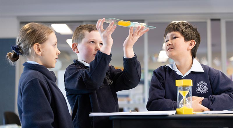 Three OLN Lawson students in science class. They are using a measuring instrument.