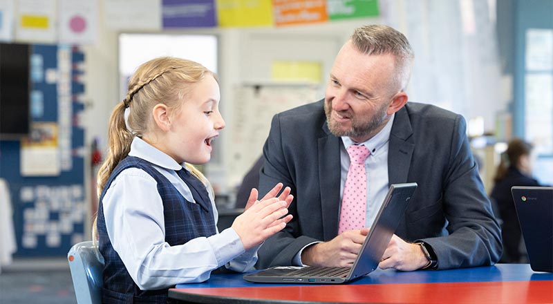 Our Lady of the Nativity Lawson Principal, Matthew Bond, and student. Matthew is assisting a student on her laptop.