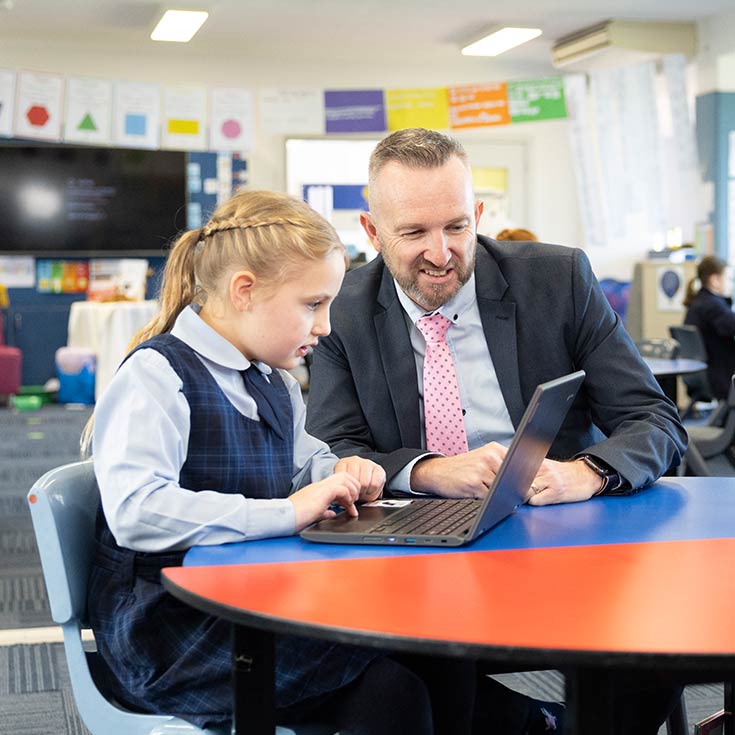 Matthew Bond, Principal of Our Lady of the Nativity Primary School Lawson, assisting student in class. The student is typing on her laptop.