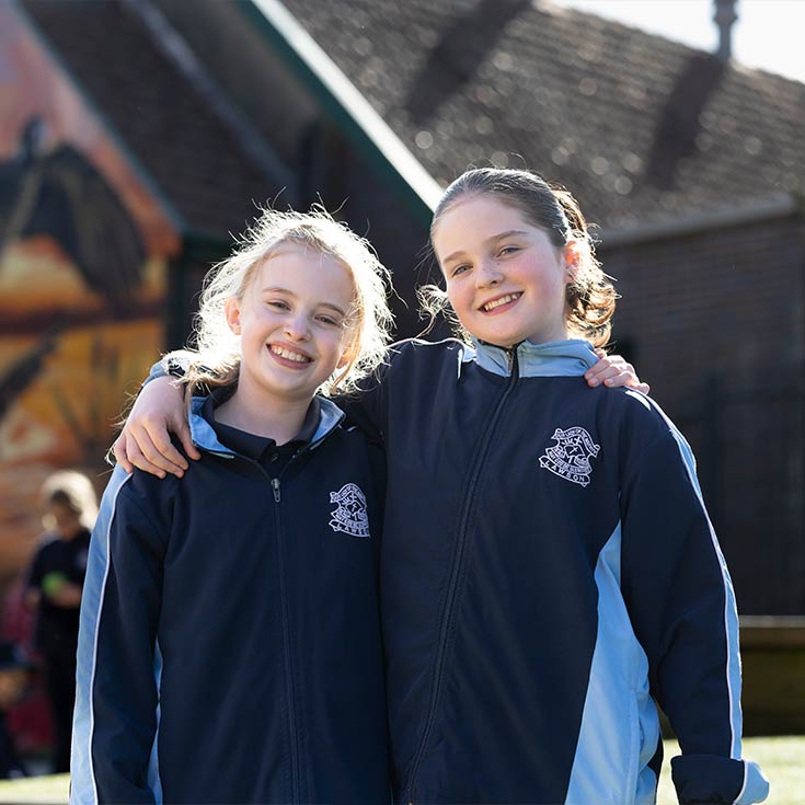 Two OLN Lawson students outdoors. They are smiling and have their arms wrapped around each other.