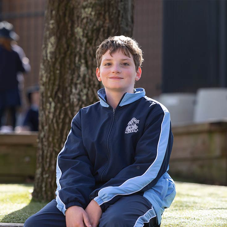 Smiling OLN Lawson student sitting under a tree