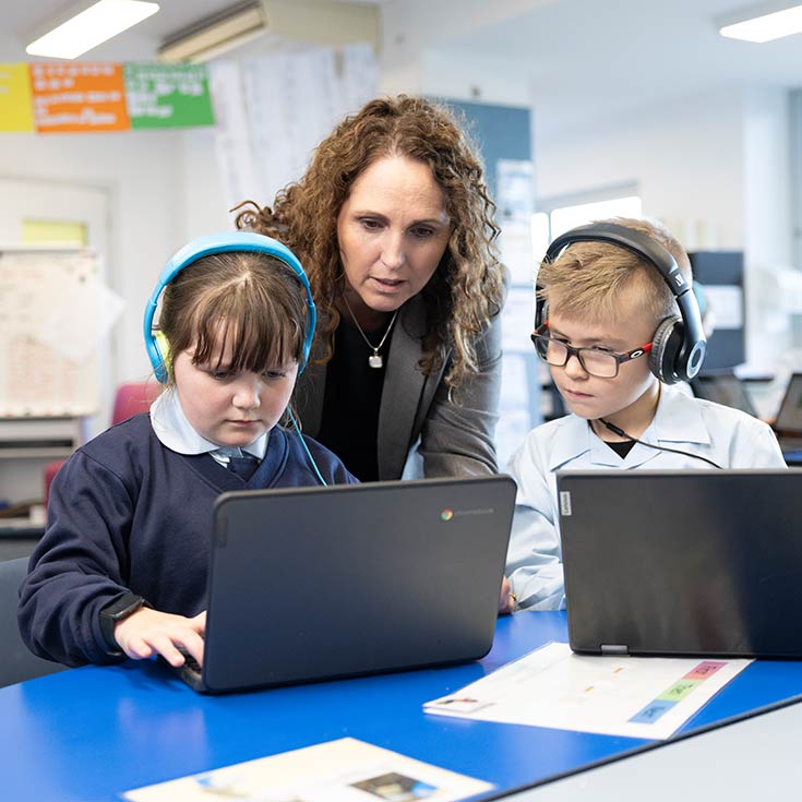 OLN Lawson teacher assisting two students who are using laptops